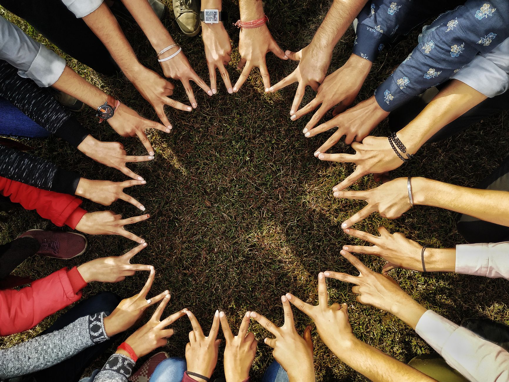 circle of hands giving a peace sign