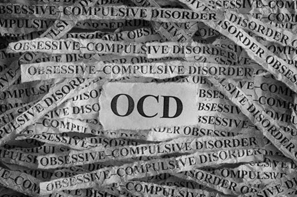 Black and white image featuring the letters 'OCD' surrounded by torn paper strips with the repeated phrases 'Obsessive-Compulsive Disorder'.